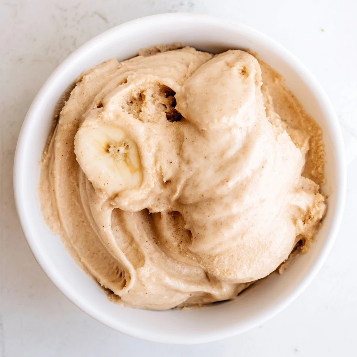 This vibrant photo shows a bowl of homemade 2-Ingredient Banana Ice Cream, perfectly smooth and sweet.