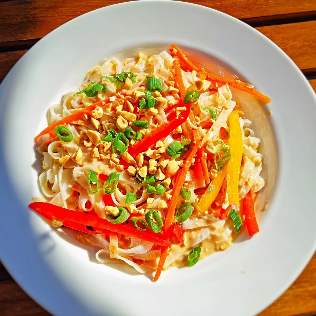 Close-up of freshly made spicy peanut noodles, garnished with peanuts and cilantro.