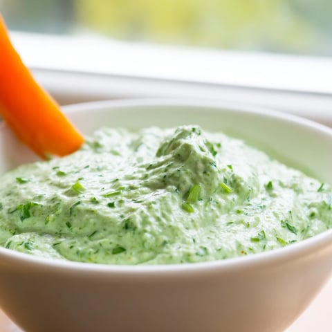 Creamy Green Goddess Salad Dip in a rustic bowl, surrounded by colorful tortilla chips and fresh vegetable crudités for dipping.