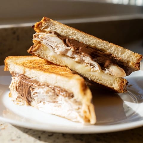 A cross-section reveals layers in the Nutella Grilled Cheese with Chicken: creamy Nutella, brie, and tender chicken.