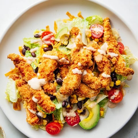 A colorful Tex-Mex salad features crunchy tortilla strips and a vibrant drizzle of creamy salsa ranch dressing.