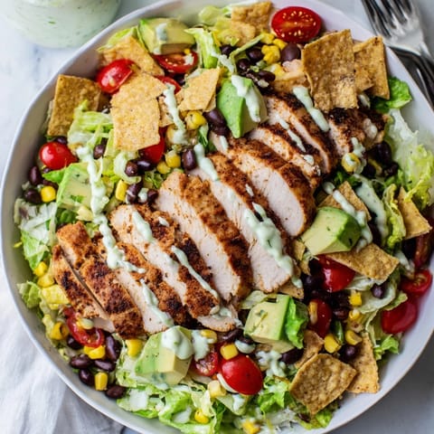 A close-up of Crunchy Taco Chicken Salad showing diced avocado, shredded cheddar cheese, and crushed gluten-free taco shell pieces mixed in.