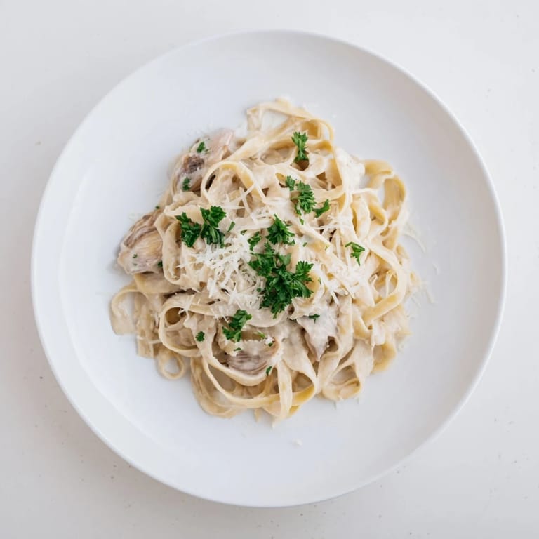 A close-up of roasted garlic cream pasta twirling on a fork, highlighting the silky texture and rich, golden sauce.