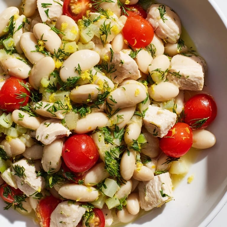 A vibrant bowl of Lemony White Bean Chicken Salad with cherry tomatoes, red onion, and fresh dill, perfect for a light lunch or summer dinner.  