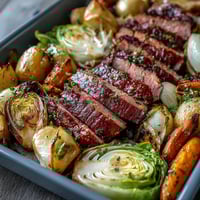 A colorful sheet pan dinner with tender corned beef slices, roasted cabbage wedges, and golden potatoes, perfect for a hearty Irish-American meal.