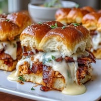 Warm Derby Day Hot Brown sliders with turkey, bacon, and creamy Mornay sauce on soft rolls, baked until golden and bubbling.  